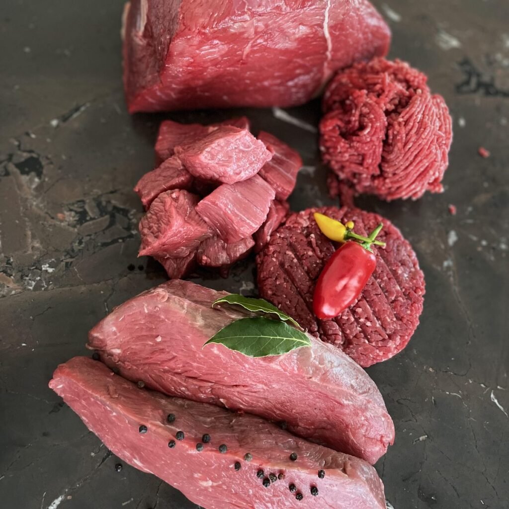 Rindfleisch wie aus einem Fleischpaket: Steaks, Gulaschwürfel, Hackfleisch und Patties auf Schiefer
