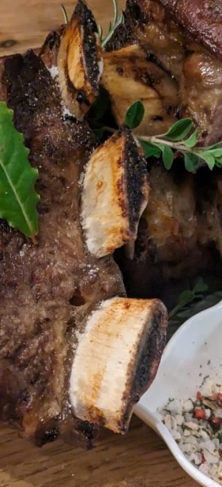 Gegrillte Rinderrippen mit Kräutern auf einem Holzbrett